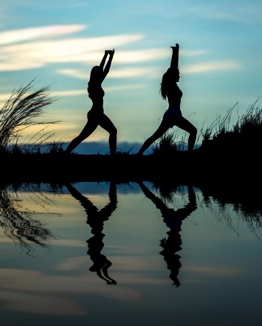 dos deportistas practicando yoga al aire libre